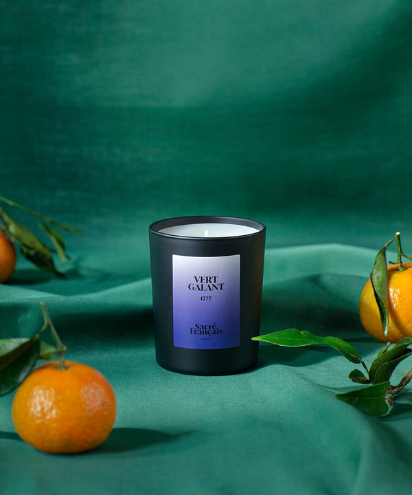 still life candle sacred french perfume green gallant with mandarins on green background